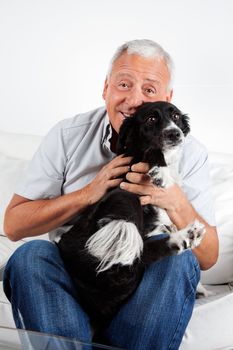 Happy senior man sitting on sofa with his dog at home
