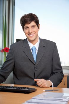 Portrait of smiling male manager sitting at his desk in office