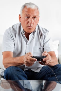 Elderly man playing video game at home