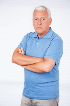 Serious senior man with arms crossed standing against white background