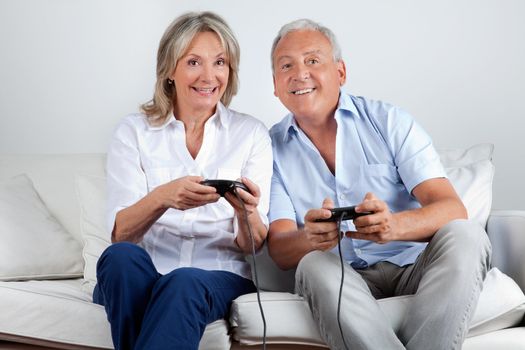 Happy senior couple playing video game at home