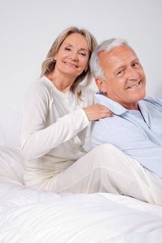 Portrait of happy couple sitting together on bed at home