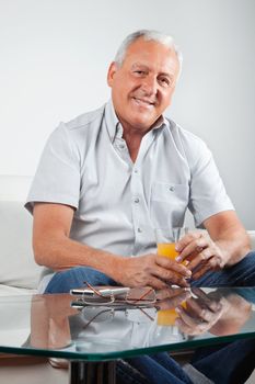 Portrait of casual senior man holding glass of orange juice