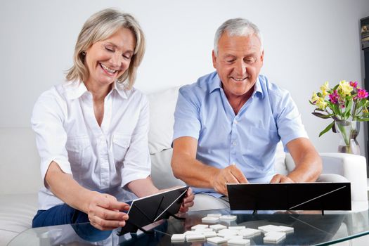 Happy senior couple playing rummy together at home.