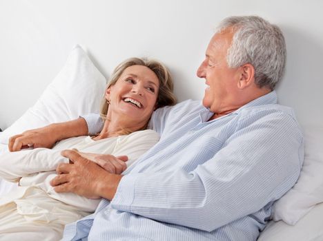 Cheerful couple relaxing on bed at home