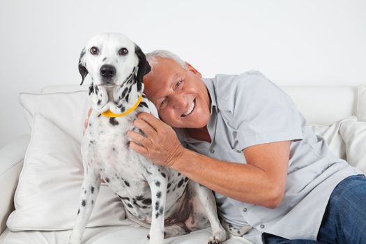Portrait of senior man sitting on sofa with his pet dog at home