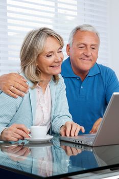 Happy couple browsing internet together on laptop