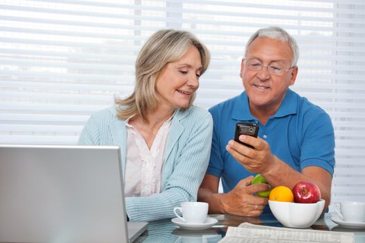 Senior man showing mobile phone to female