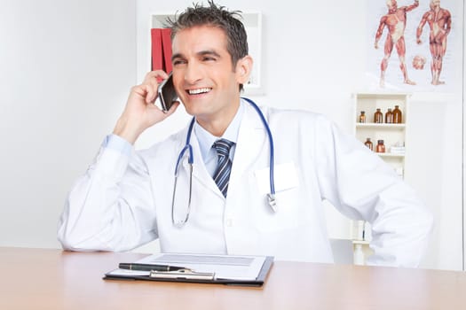Doctor talking on mobile phone, sitting at desk .