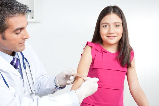 Doctor applying bandage on hand of a little girl child.