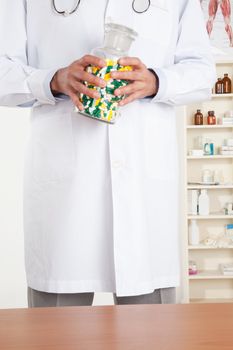 Male doctor holding a bottle with pills.