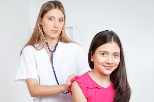 Female doctor examining child patient in clinic.