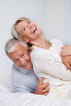 Excited senior couple laughing together on bed