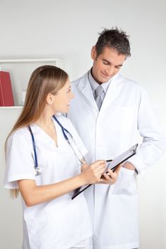 Smiling female doctor showing clipboard to the male doctor.