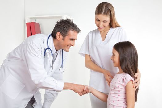 Doctor shaking hand with girl child patient.