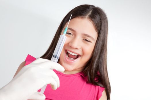 Doctor hand holding injection in front of girl.