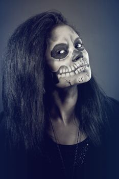 Young woman in day of the dead mask skull face art. Halloween face art with fog on black background