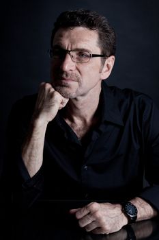 attractive adult man with glasses and black shirt on black background