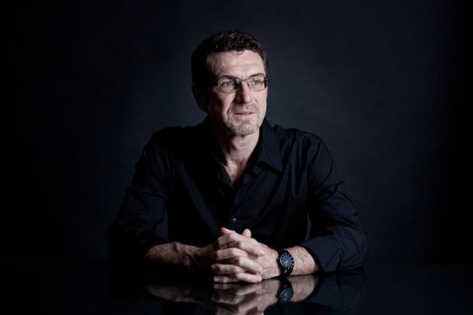 attractive adult man with glasses and black shirt on black background