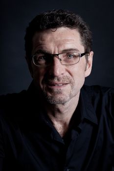 attractive adult man with glasses and black shirt on black background