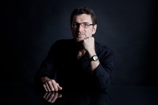 attractive adult man with glasses and black shirt on black background