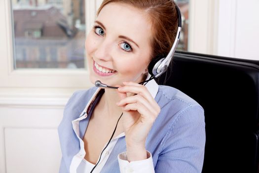 smiling young female callcenter agent with headset in office
