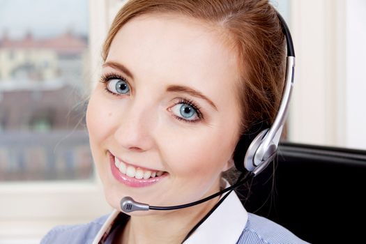 smiling young female callcenter agent with headset in office