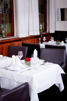 tables in restaurant with white tablecloth and elegant dish and silverwear