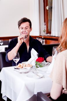 man and woman in restaurant for dinner drinking red wine and smiling