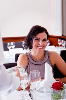 man and woman for dinner in restaurant waiter serving mineral water 