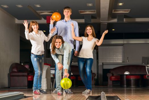 Group of young friends playing bowling, spending time with friends