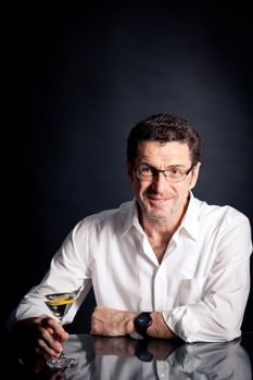 adult man holding an alcoholic drink thoughtful on black background