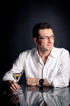 adult man holding an alcoholic drink thoughtful on black background