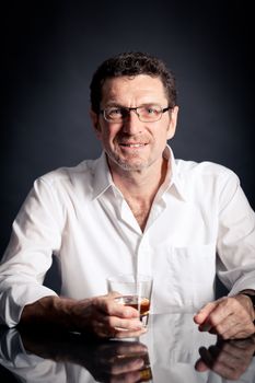 adult man holding an alcoholic drink thoughtful on black background