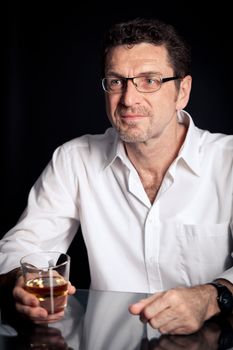 adult man holding an alcoholic drink thoughtful on black background