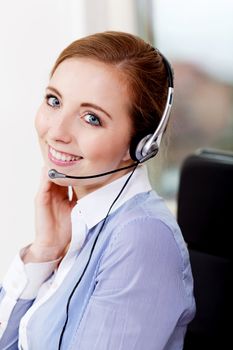 smiling young female callcenter agent with headset in office