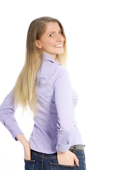 Attractive middle-aged blond woman dressed in jeans with her hands in her pockets standing looking back over her shoulder on white