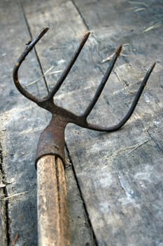 Sharp pitchfork at the wooden background