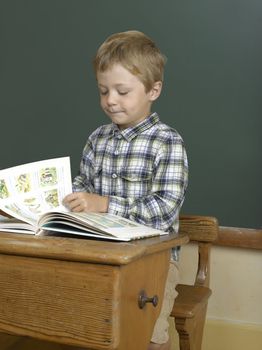 jeune garçon sur un banc d'école devant un fond de tableau