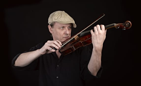 Portrait of a man playing  wooden violin on black background