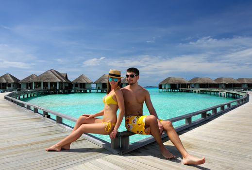 Couple on a tropical beach jetty at Maldives