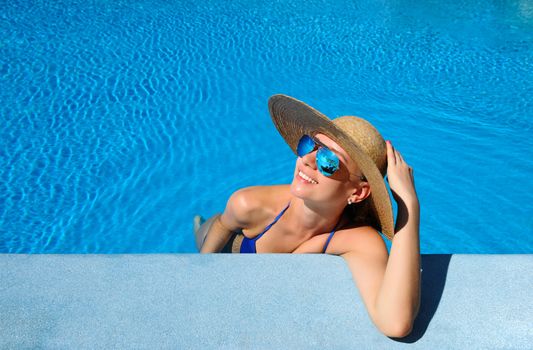 Woman in hat relaxing at the pool 