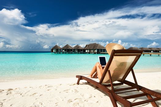 Young woman in hat with tablet pc at the beach