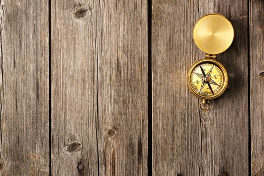 Antique brass compass over wooden background