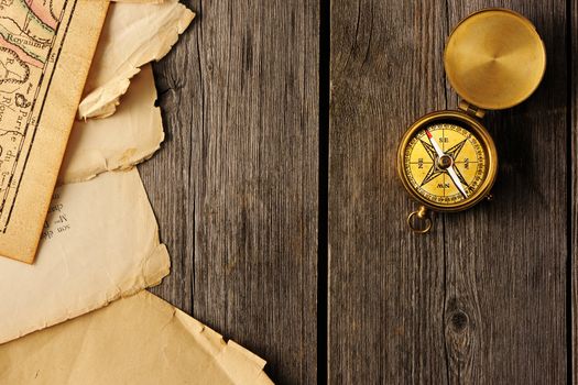 Antique brass compass over wooden background