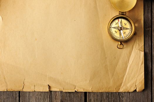 Antique brass compass over old paper background