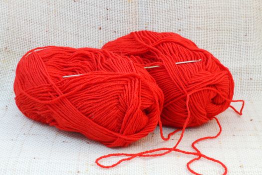 Close up of two red balls (clews) of yarn and knitting hook