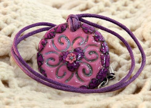 clay handmade red and violet flower on a knitted background