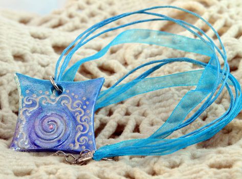 clay handmade blue amulet on a kntited background