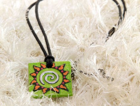 clay handmade green amulet (sun) on a knitted background